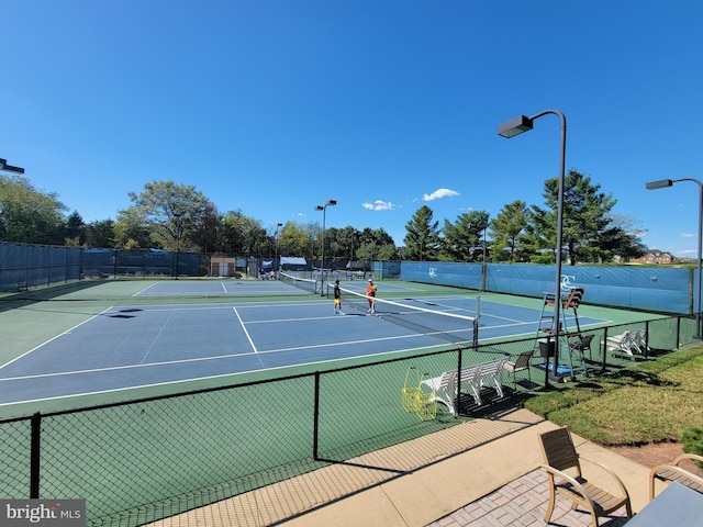 view of tennis court featuring fence and community basketball court