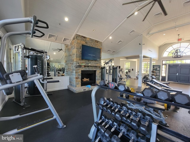 workout area featuring visible vents, high vaulted ceiling, and a stone fireplace
