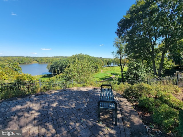 view of patio / terrace featuring fence and a water view