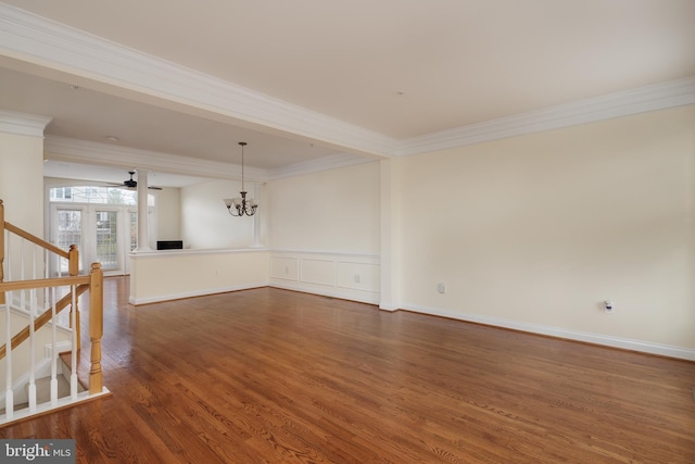 spare room with ornamental molding, stairs, ceiling fan with notable chandelier, and wood finished floors