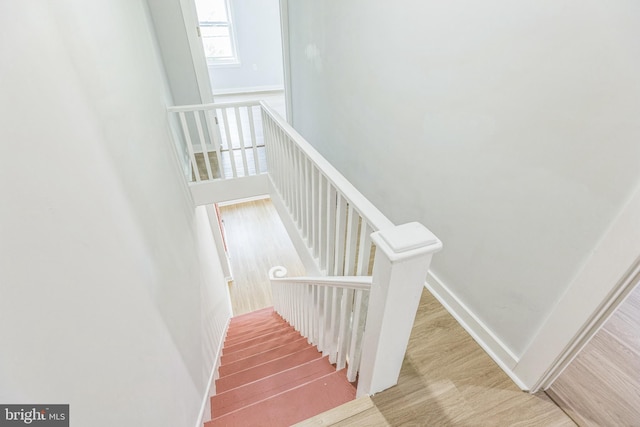 staircase featuring baseboards and wood finished floors