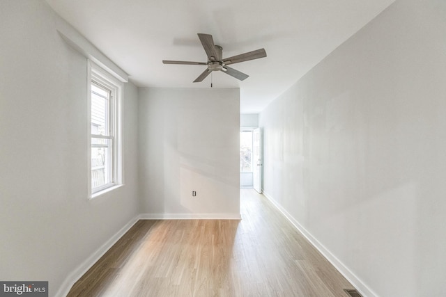 spare room with light wood-style floors, a ceiling fan, and baseboards