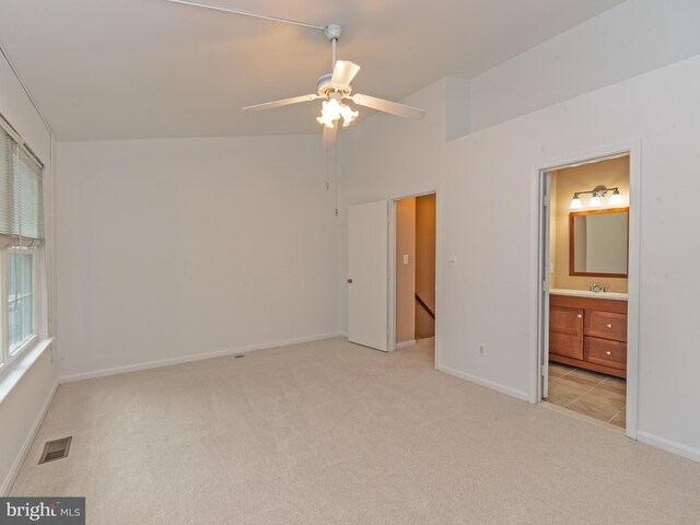 unfurnished bedroom featuring visible vents, baseboards, ensuite bathroom, light colored carpet, and a sink
