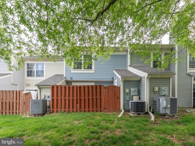 back of property featuring central AC unit, fence, and a yard