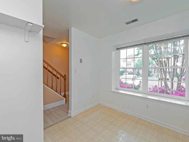 unfurnished room featuring visible vents, tile patterned floors, stairs, and baseboards
