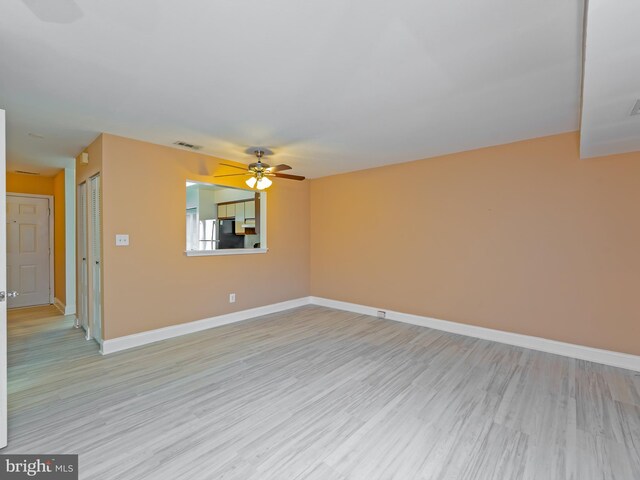 spare room featuring a ceiling fan, baseboards, visible vents, and light wood-style flooring