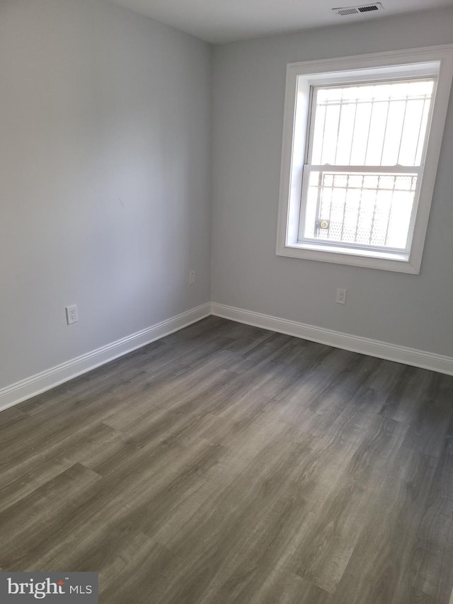 empty room featuring baseboards and dark wood-style flooring