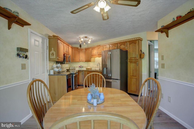 dining room featuring baseboards, a ceiling fan, and a textured ceiling