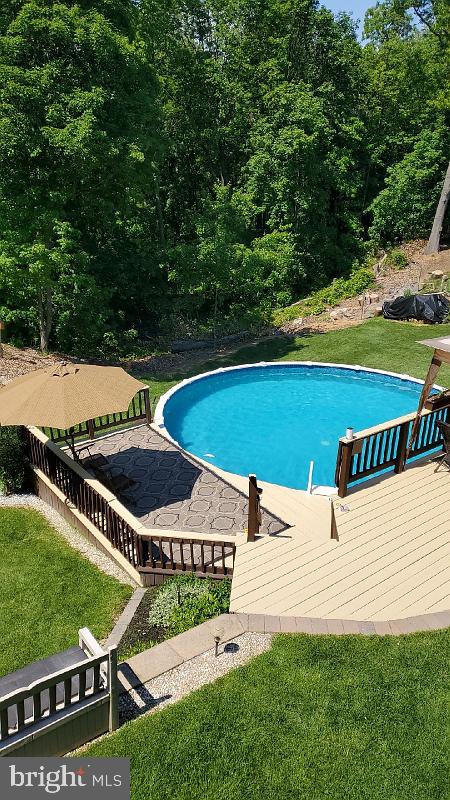 outdoor pool with a lawn and a wooden deck