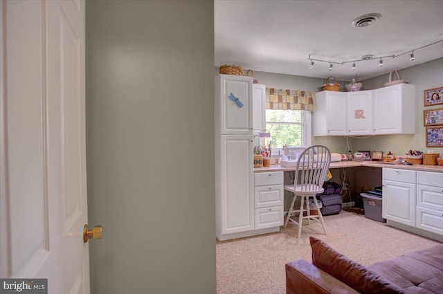 office featuring visible vents, built in desk, and light carpet