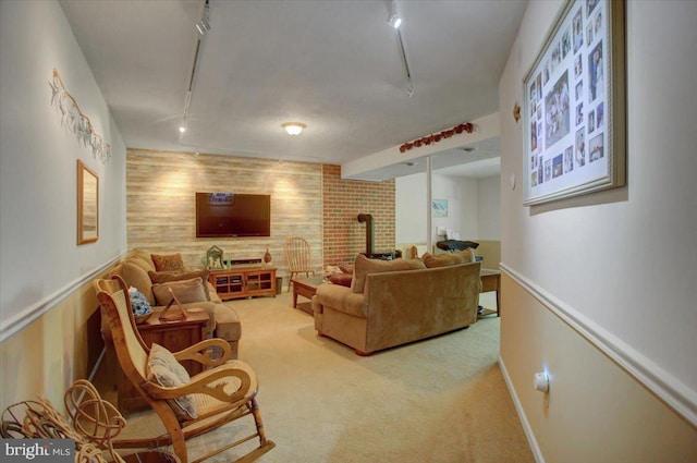 carpeted living area featuring wooden walls, track lighting, an accent wall, and a wood stove