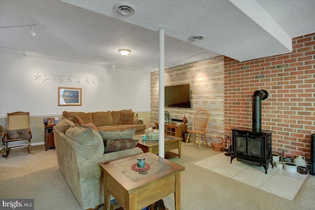 carpeted living room with visible vents, a wood stove, a textured ceiling, and track lighting