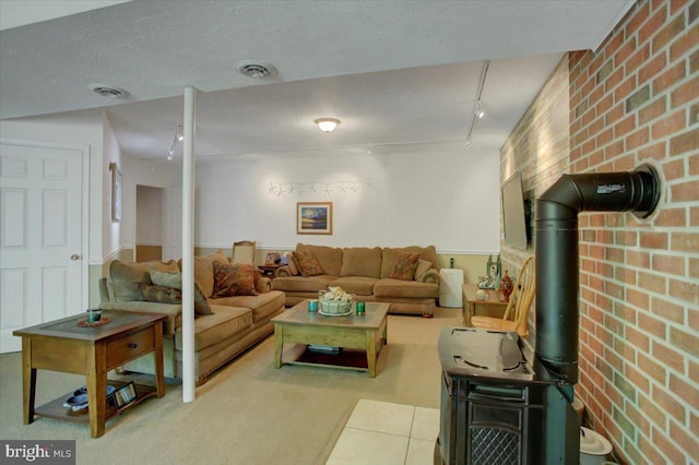 living area with rail lighting, visible vents, a wood stove, and brick wall