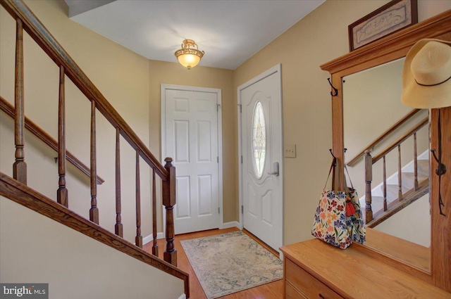 foyer with stairs, baseboards, and wood finished floors