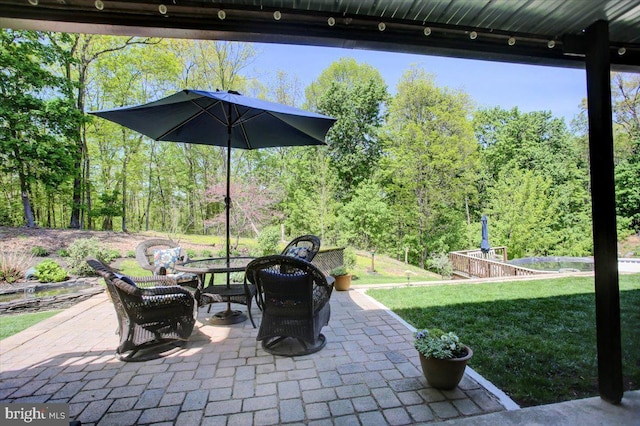 view of patio / terrace with a wooded view and outdoor dining space
