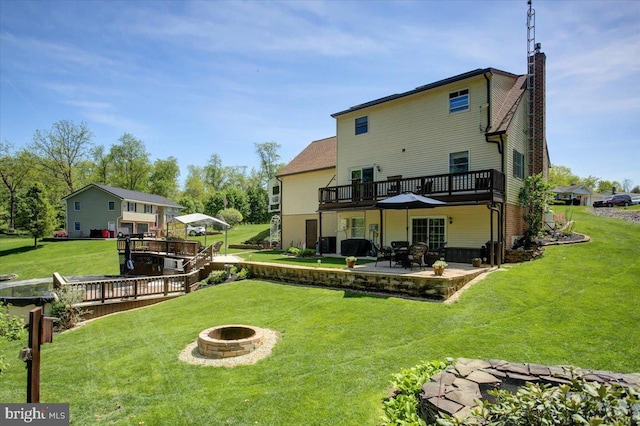 rear view of house featuring a patio, an outdoor fire pit, a wooden deck, and a chimney