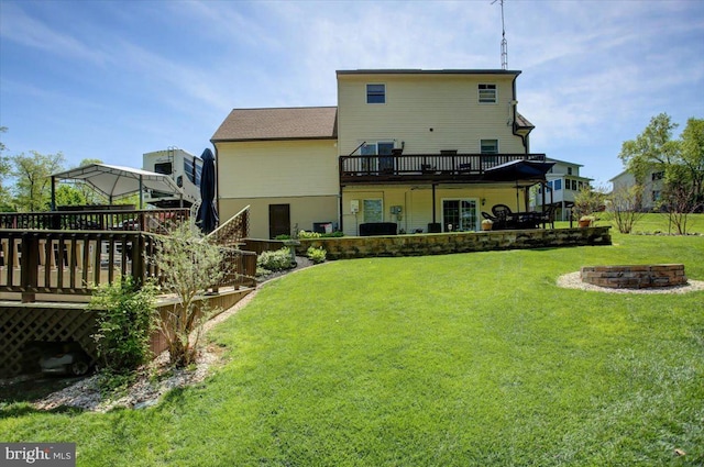 back of property with a fire pit, a wooden deck, and a yard