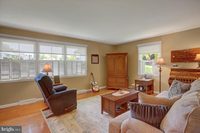 living room featuring plenty of natural light, baseboards, and light wood finished floors