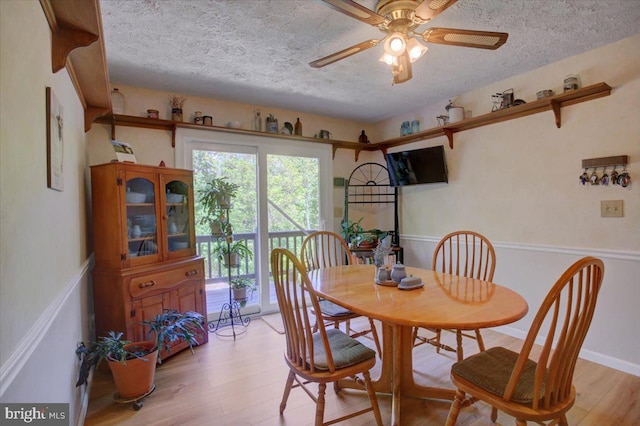 dining space with a ceiling fan, light wood finished floors, and a textured ceiling