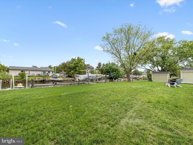 13295 Rollie Road E Rd, Bishopville, MD 21813 - view of green lawn with a boat dock, boat lift, an outbuilding, a shed, and a water view