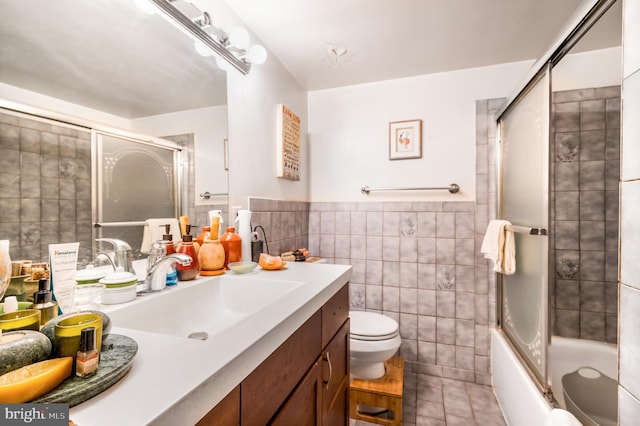 bathroom featuring tile walls, tile patterned floors, vanity, toilet, and wainscoting