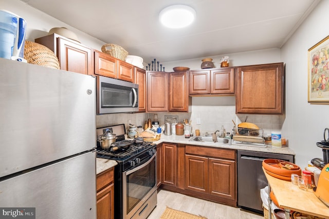 kitchen with appliances with stainless steel finishes, a sink, light countertops, and decorative backsplash