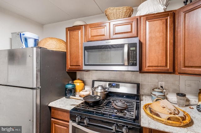 kitchen with stainless steel appliances, tasteful backsplash, and brown cabinets