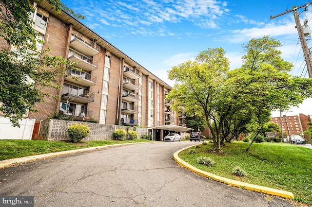 view of apartment building / complex with covered parking and fence