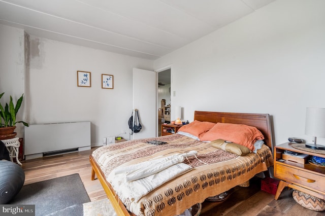 bedroom with radiator heating unit and light wood-type flooring