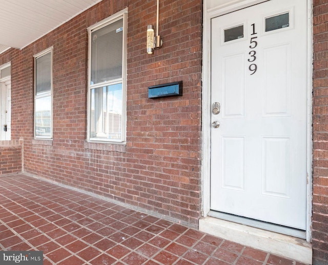 entrance to property with covered porch and brick siding