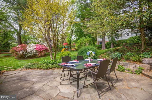 view of patio featuring a playground, fence, and outdoor dining space