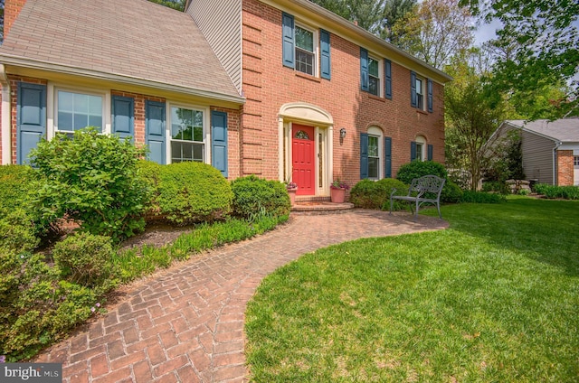 colonial home with brick siding and a front yard