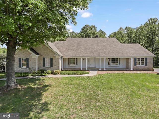 ranch-style house featuring covered porch, a shingled roof, and a front lawn