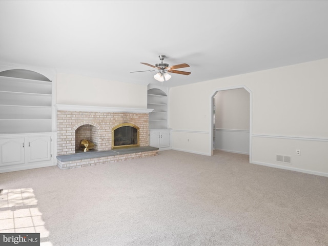 unfurnished living room with a ceiling fan, light colored carpet, visible vents, built in features, and a fireplace