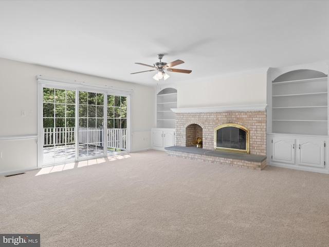 unfurnished living room with ceiling fan, visible vents, a fireplace, built in shelves, and carpet flooring