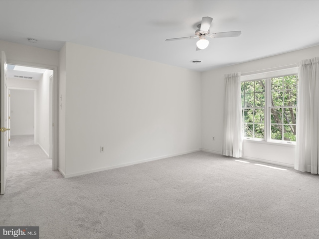 carpeted spare room with visible vents, a ceiling fan, and baseboards