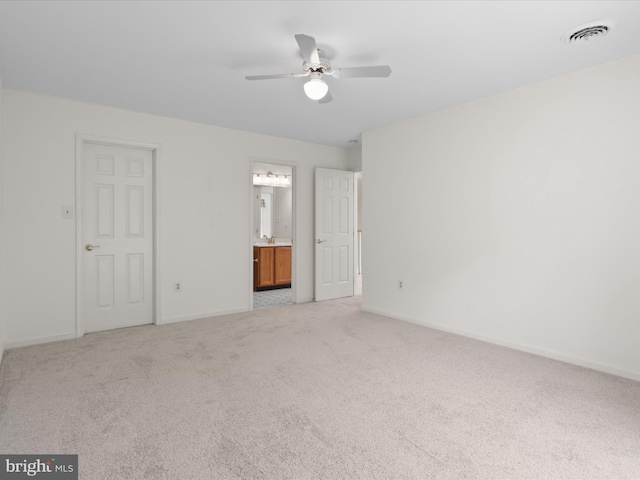 unfurnished bedroom with baseboards, light colored carpet, visible vents, and ensuite bath