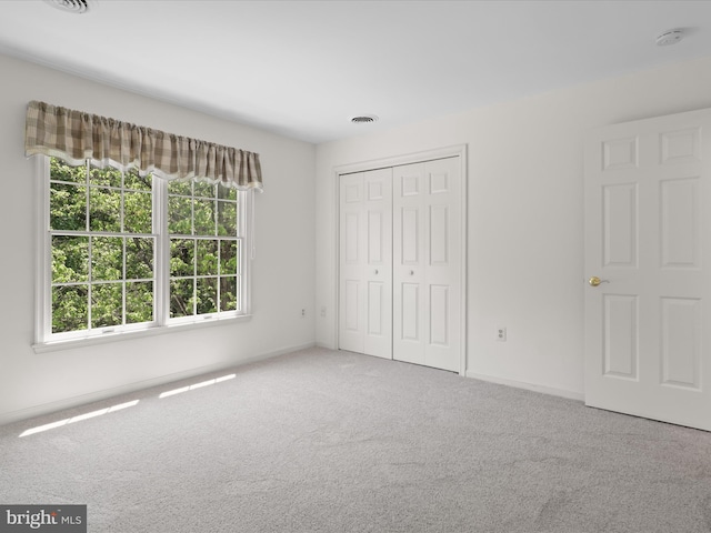 unfurnished bedroom with visible vents, carpet, baseboards, and a closet