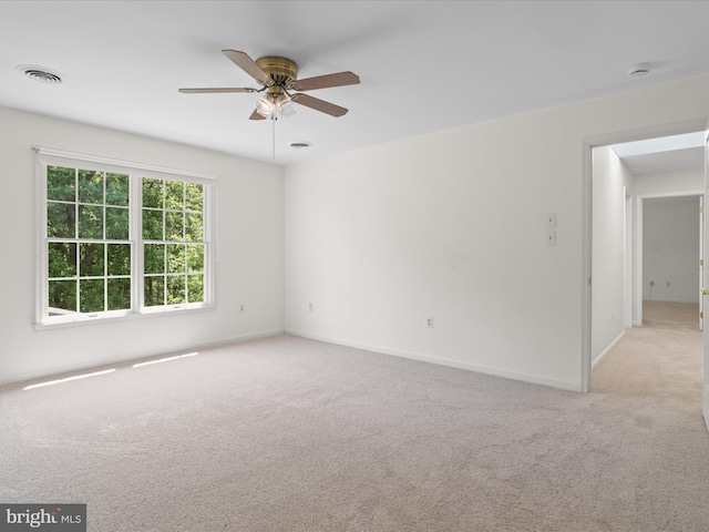 spare room with visible vents, baseboards, ceiling fan, and light carpet