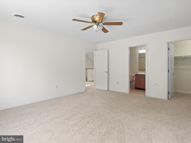 unfurnished bedroom with light colored carpet, a walk in closet, visible vents, and a closet