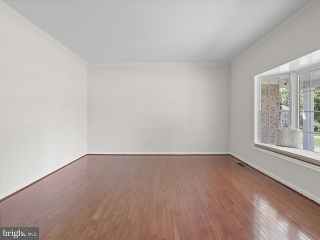 unfurnished room featuring wood-type flooring, baseboards, and crown molding
