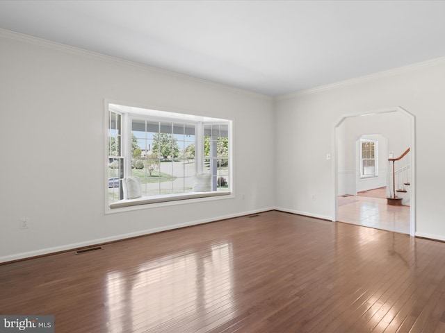empty room with arched walkways, visible vents, ornamental molding, and a healthy amount of sunlight