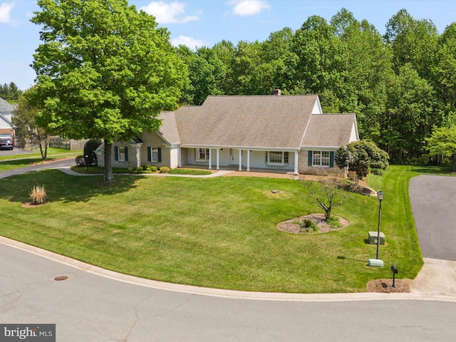 view of front of home featuring a shingled roof, a front lawn, covered porch, and a chimney