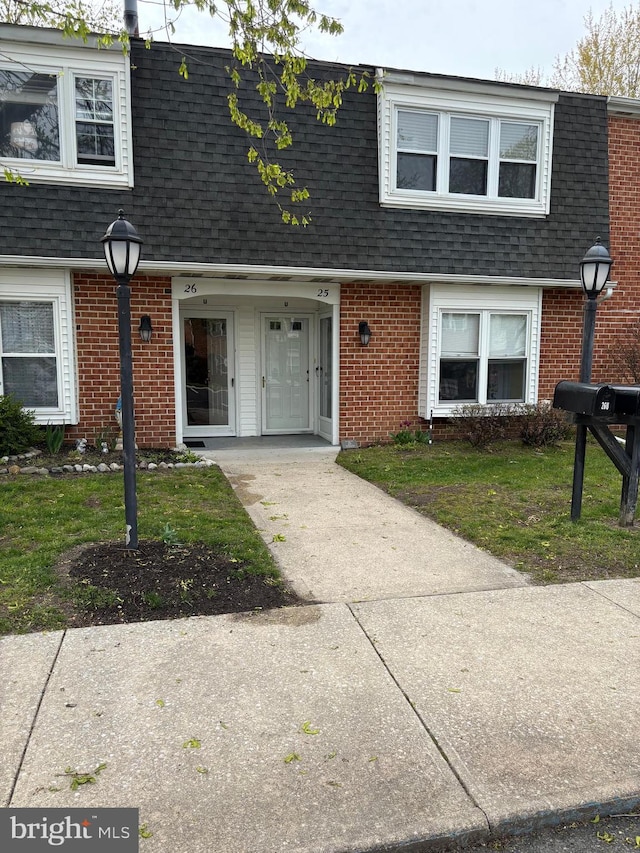 view of front of property featuring brick siding and a shingled roof