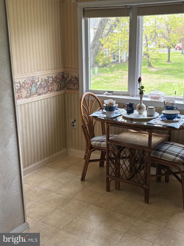 dining room featuring light tile patterned flooring, wallpapered walls, and a wainscoted wall