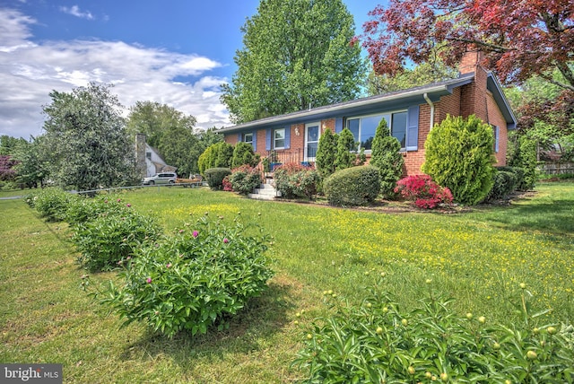 view of front of home featuring brick siding, a chimney, and a front yard