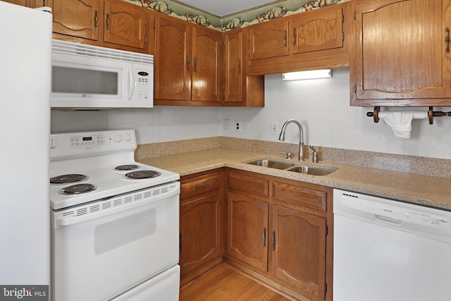 kitchen with white appliances, a sink, light countertops, and brown cabinets