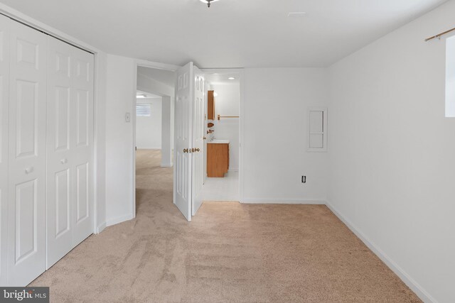 unfurnished bedroom with carpet flooring, a closet, baseboards, and connected bathroom