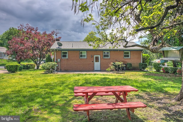 back of property featuring a yard and brick siding