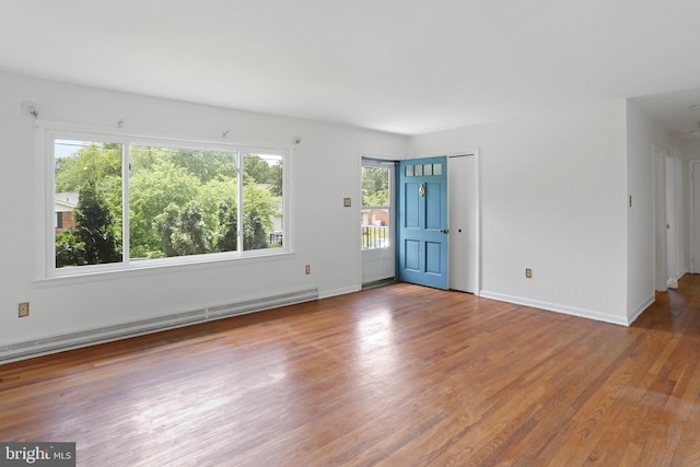 spare room featuring baseboard heating, wood finished floors, and baseboards